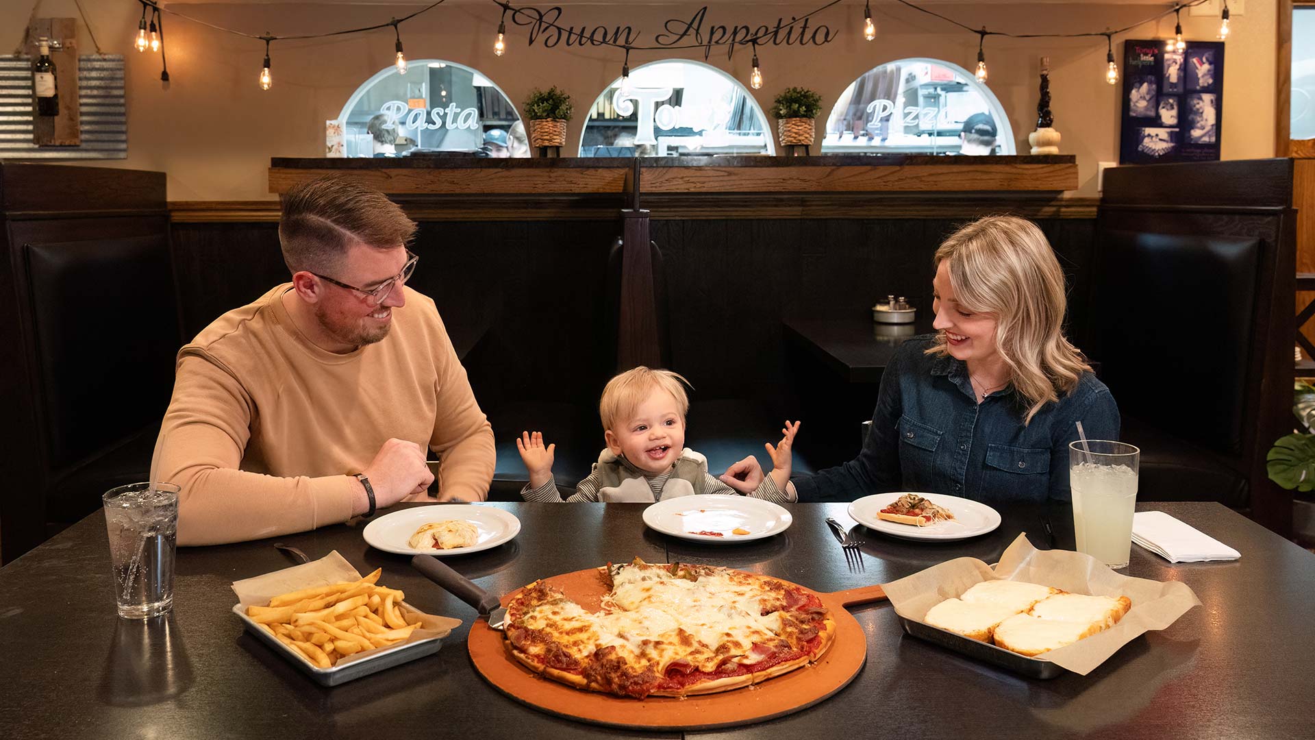 Family sitting down enjoying pizza and sides at Tony's Pizza